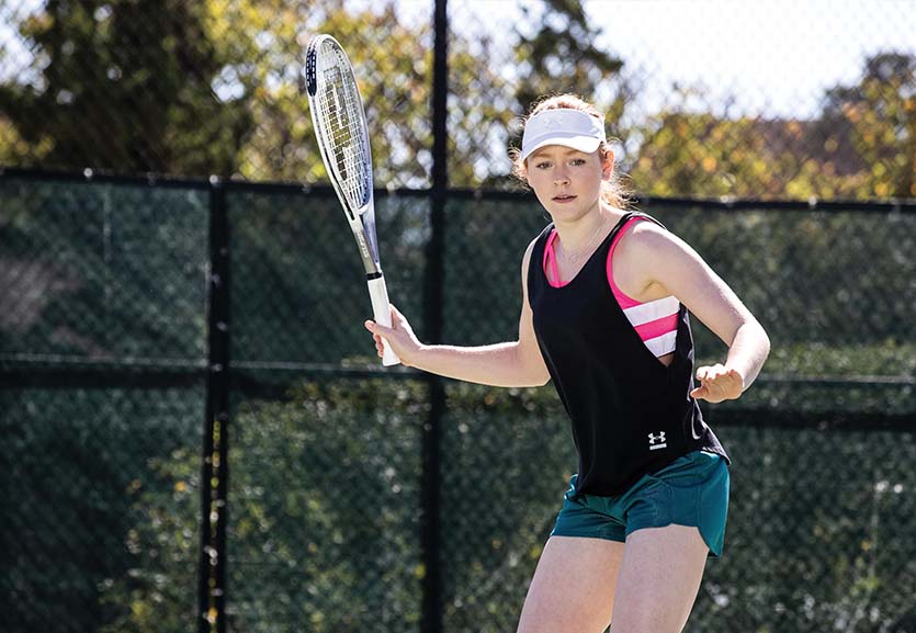 A girl holds a tennis racquet on a court.