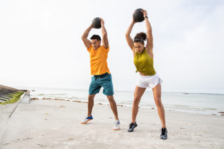 two people doing slam ball exercises at the beach wearing high-intensity shoes
