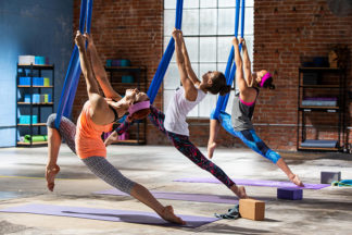 three women practice aerial yoga