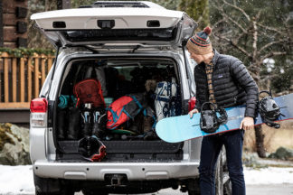 Man loads snowboarding equipment into trunk of his van.