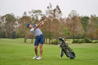 A man swings an iron on the golf course.