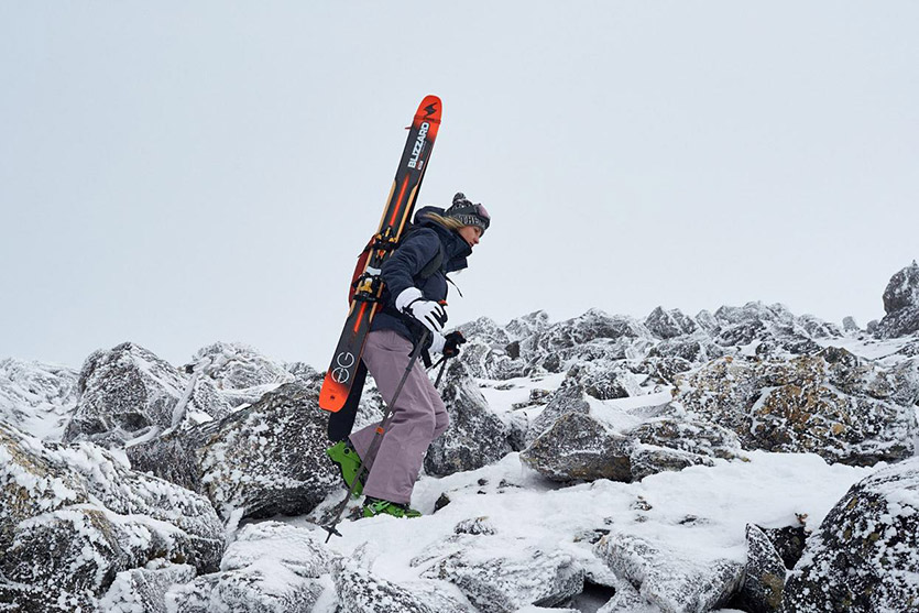 A woman climbs a snowy terrain.