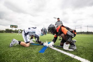 Two lacrosse players compete in a faceoff.