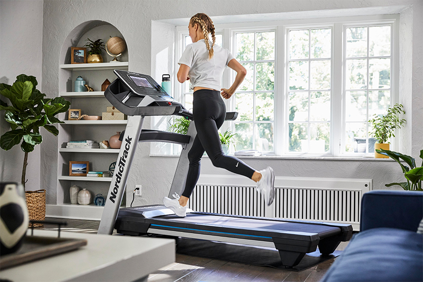 Image features woman running indoors on a treadmill.