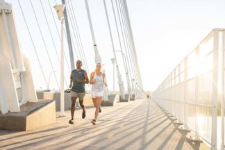 A male and female running on a bridge