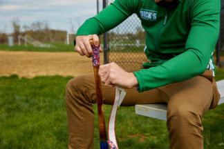 baseball player regripping and taping baseball bat with lizard skins bat tape