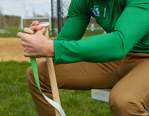 baseball player taping and regripping bat with bat tape at a baseball field