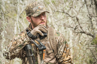 man in woods wearing camo with a hunting rangefinder