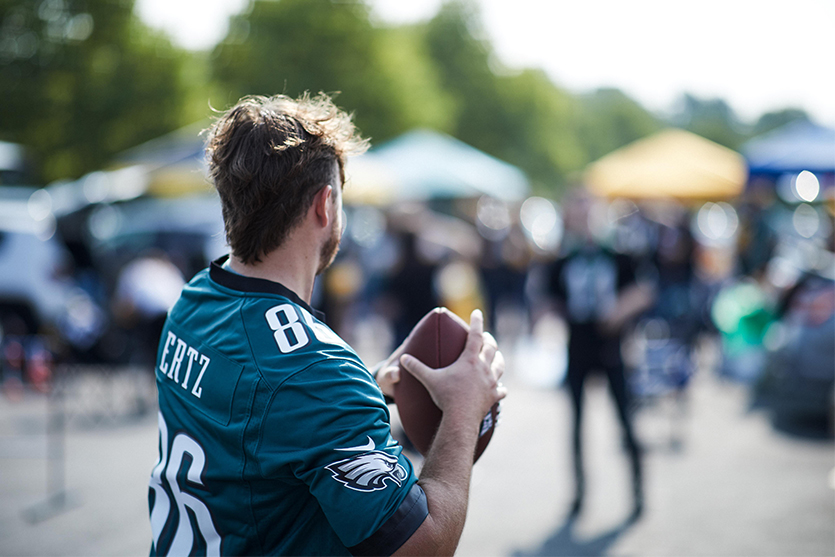 man at tailgate wearing Ertz Philadelphia Eagles jersey playing catch with a football