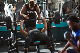 Male Gym-Goer Spotting Workout Partner On Bench Press In Gym