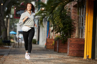 woman running at night wearing adidas fanny pack, adidas pullover, adidas joggers and adidas shoes