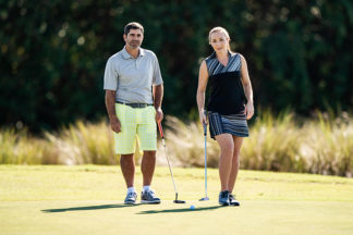 man and woman golfing on the putting green