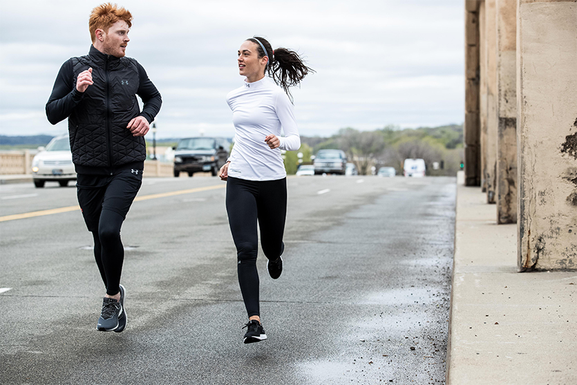 man and woman running on the road in the fall wearing running tights and long sleeves