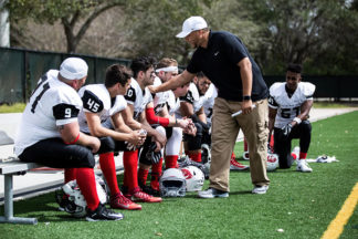 football coach talking to his team sitting on the bench at a game