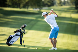 Male Golfer Swinging Club on Golf Course