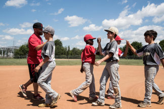 Baseball Coach And Players High-Fiving After A Game