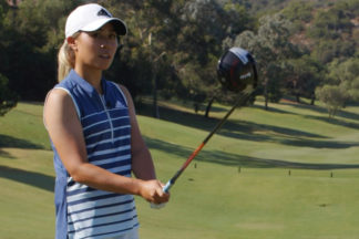 Danielle Kang holding a driver on a golf course wearing adidas golf apparel