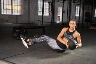 woman wearing nike fitness outfit doing Russian Twists with a medicine ball