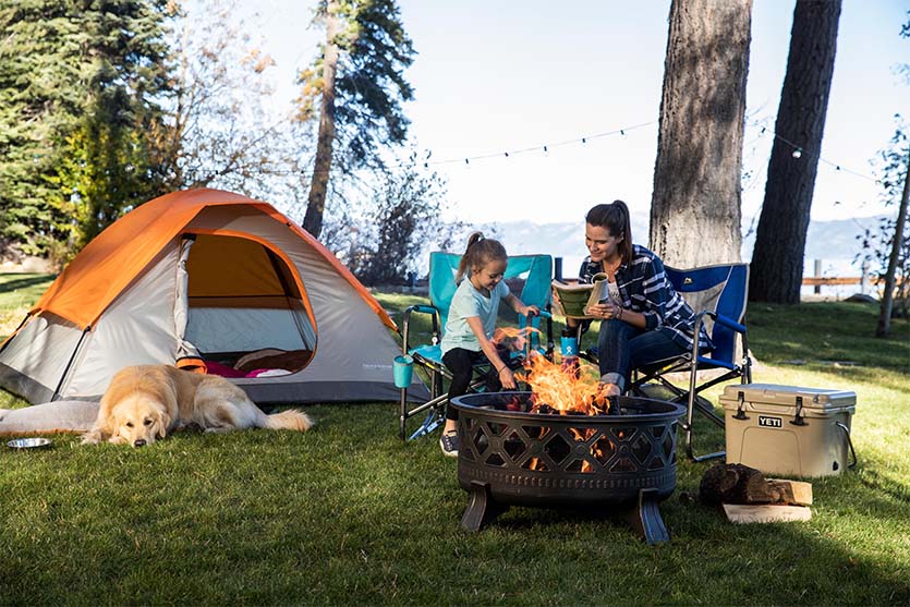 mom and daughter in their backyard camping with their golden retriever