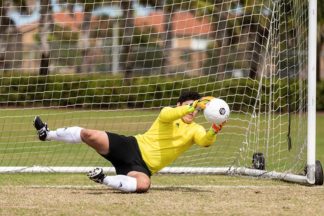 soccer goalkeeper dives to catch the soccer ball on the soccer field