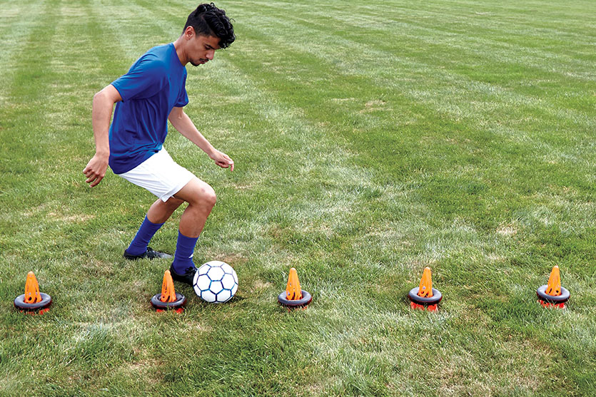 male soccer player training with soccer training cones