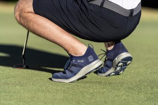 A man kneeling in golf shoes.